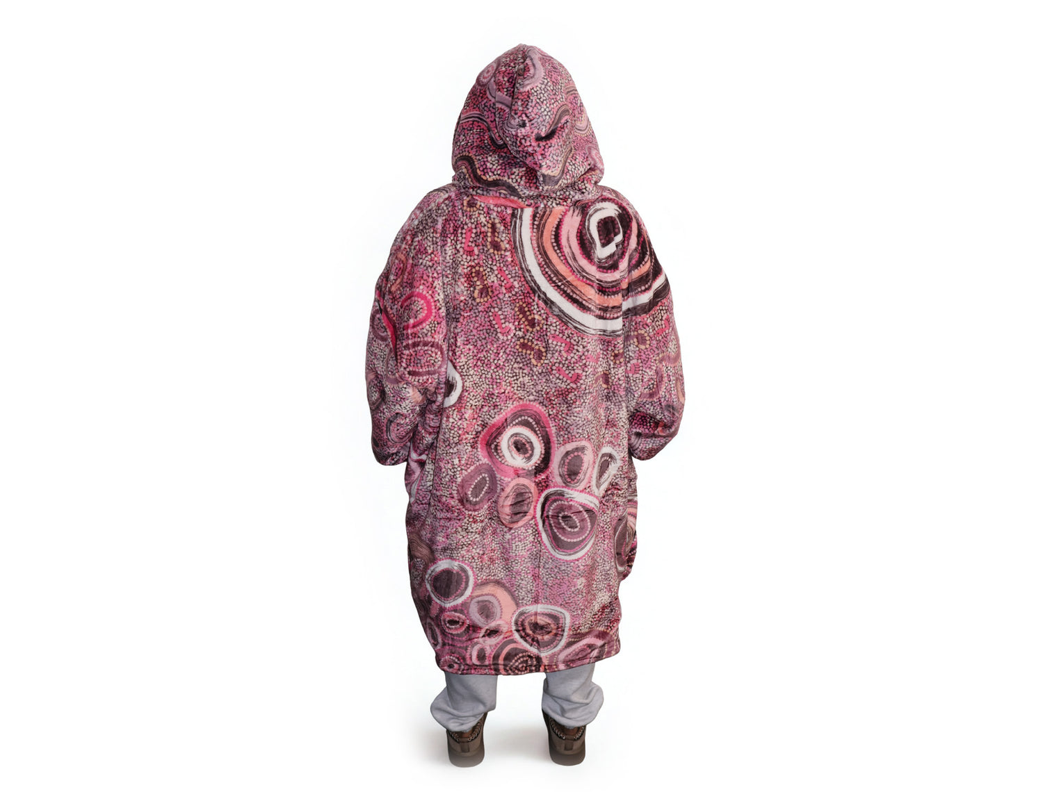 Woman wearing pink oversized hooded blanket with Indigenous-inspired artwork and plush fleece lining