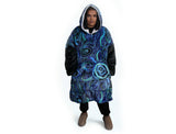 Woman wearing oversized blue rain Aboriginal art hooded blanket with sherpa lining and front pocket