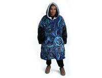 Woman wearing oversized blue rain Aboriginal art hooded blanket with sherpa lining and front pocket