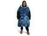 Woman wearing oversized blue rain Aboriginal art hooded blanket with sherpa lining and front pocket