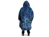 Woman wearing oversized blue rain Aboriginal art hooded blanket with sherpa lining and front pocket