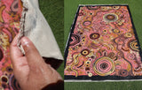 Colorful aboriginal art abstract patterned fabric held by a hand.