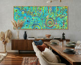 Colorful abstract aboriginal art painting on a wall above a wooden console table in a living room.