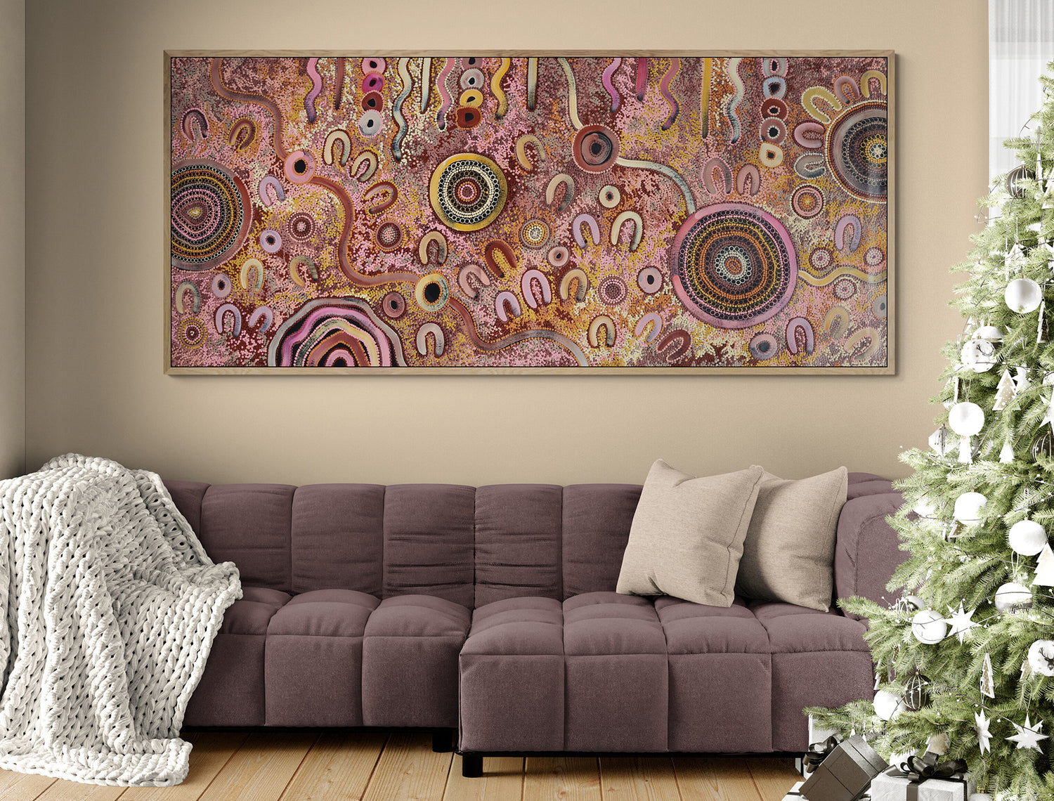 Decorative abstract aboriginal art painting on a wall above a sofa with a Christmas tree to the right.