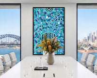 Bright contemporary interior featuring Listen Learn Teach, a large framed Aboriginal artwork in blue, turquoise, black, and white dot patterns displayed above a light wood cabinet beside tall sunlit windows