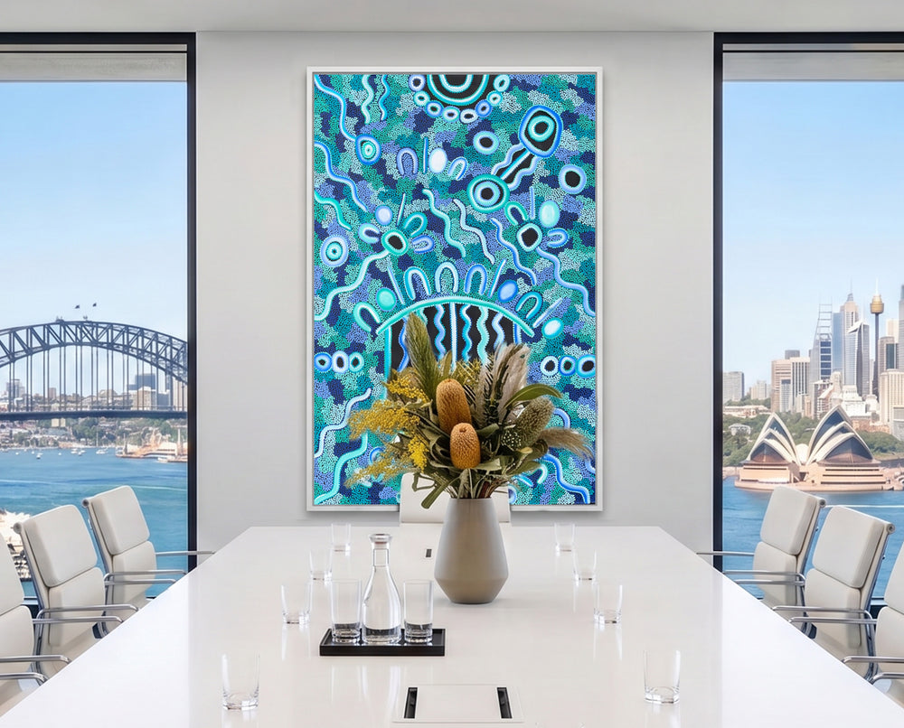 Bright contemporary interior featuring Listen Learn Teach, a large framed Aboriginal artwork in blue, turquoise, black, and white dot patterns displayed above a light wood cabinet beside tall sunlit windows