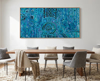 Dining room with a large abstract blue rain aboriginal art painting on the wall above a wooden table and chairs.