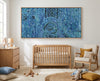 Nursery room with wooden crib, rocking chair, and abstract blue rain aboriginal art artwork on the wall.