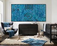 Modern nursery with a large blue rain aboriginal art abstract painting, dark wood dresser, and baby crib.