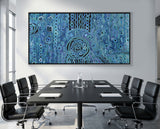 Boardroom with a large abstract blue rain aboriginal art painting on the wall above a conference table with chairs.