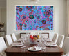 Dining room with a colorful abstract aboriginal art by T'keyah Ware painting on the wall above a set luxury dining table.