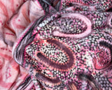 Woman wearing pink oversized hooded blanket with Indigenous aboriginal inspired artwork and plush fleece lining